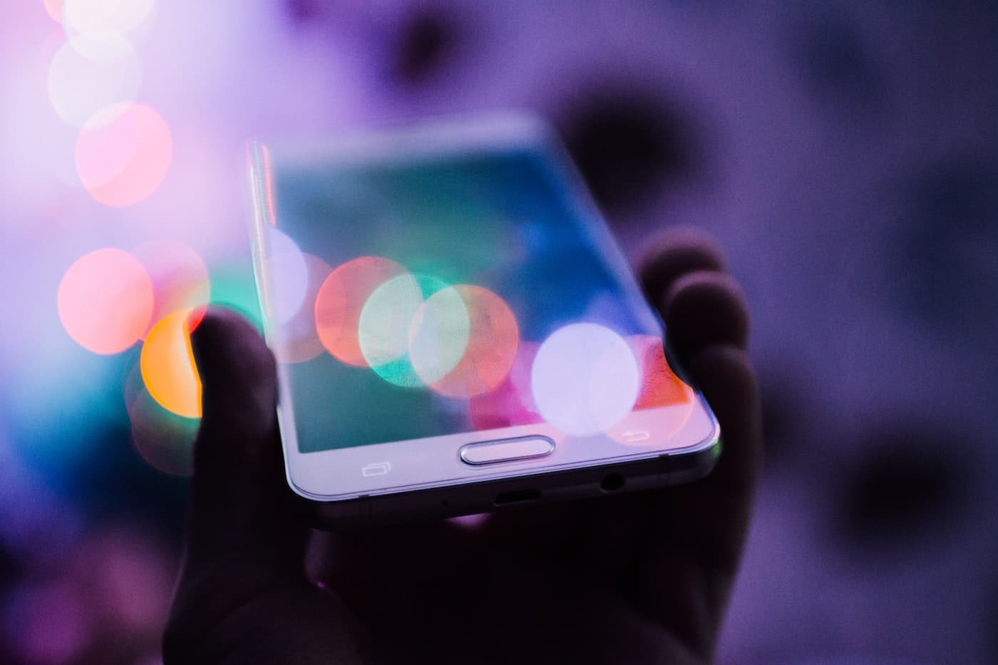 A hand holding a phone in soft window light — the hour you sit with a thread.